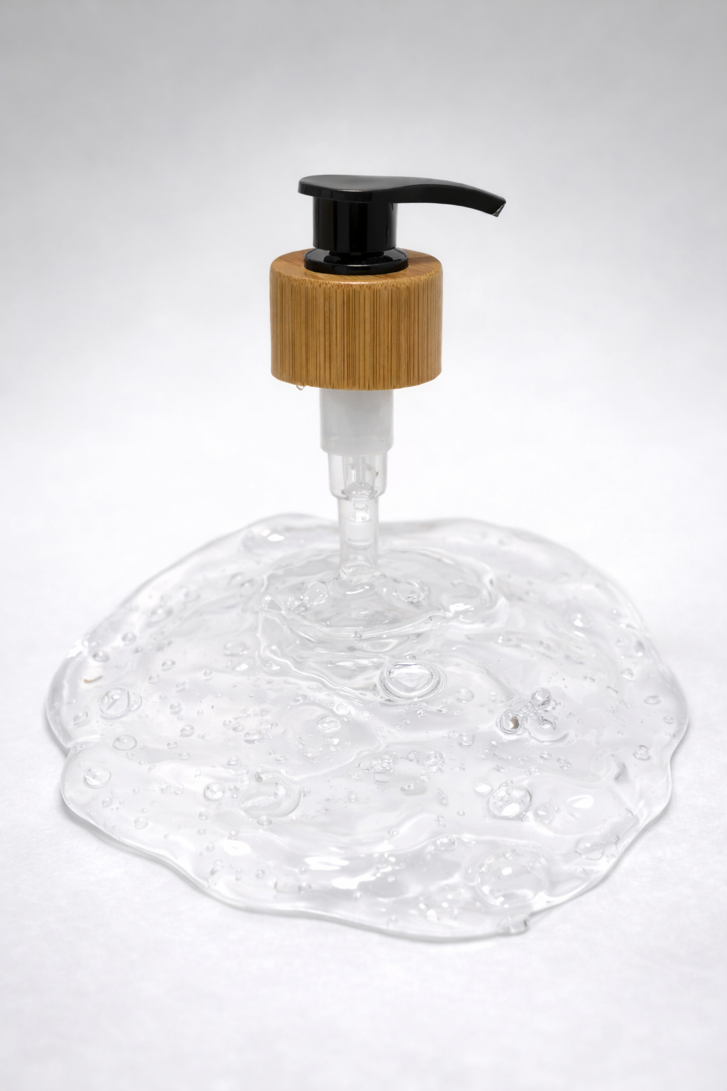A bamboo-collared soap pump above a pool of clear plant-based formula — the bottle is incidental, the formula is the point.